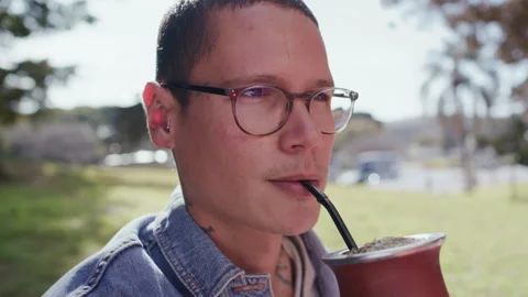Close Up of Young Man Drinking Yerba Mate Tea in Sunlit Park Stock Footage 345388615