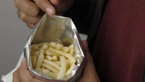 Close up Young man eating Crispy Corn rings salty snacks in paper bag. Fast food Stock Footage 152806438