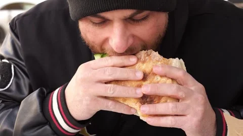 Close-up of Young Man Eating a Fresh Doner Kebab Sandwich Outdoors Vídeo Stock 332137356