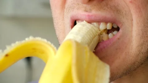 Close up of a young man eating a yellow banana Stock Footage 337830954