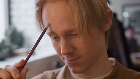 Close up of young man examining object in soft indoor lighting with blurred Stock Footage 344869827
