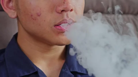 Close-up of young man exhaling thick vapor from electronic cigarette or vape Stock Footage 332388964
