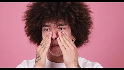 Close-up of a young man with a fluffy afro applying facial cleanser 스톡 동영상 269136929