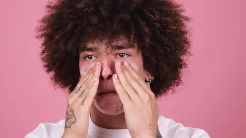 Close-up of a young man with a fluffy afro applying facial cleanser Stock Footage 269362971