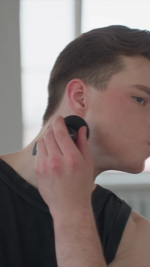 Close up of young man with geometric neck tattoo applying makeup indoors showing Stock Footage 344411644