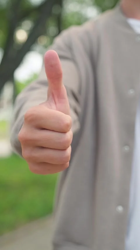 Close up of a young man giving a thumbs up gesture of approval outdoors. Pe.. Vídeo Stock 339556615