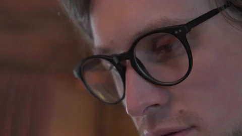 Close-Up Of A Young Man With Glasses Reading A Book In His Apartment Stock Footage 137733295