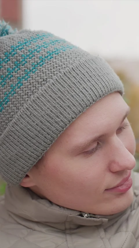 Close up of young man in gray knit beanie and beige quilted jacket standing Stock Footage 345543692