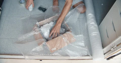 Close up young man hands packing with bubble wrap medium size parcel to delivery 動画素材 162041615