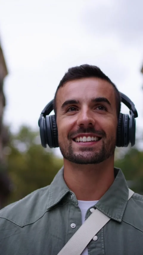 Close up young man with headphones strolling enjoys listening music nodding in Stock Footage 267485375