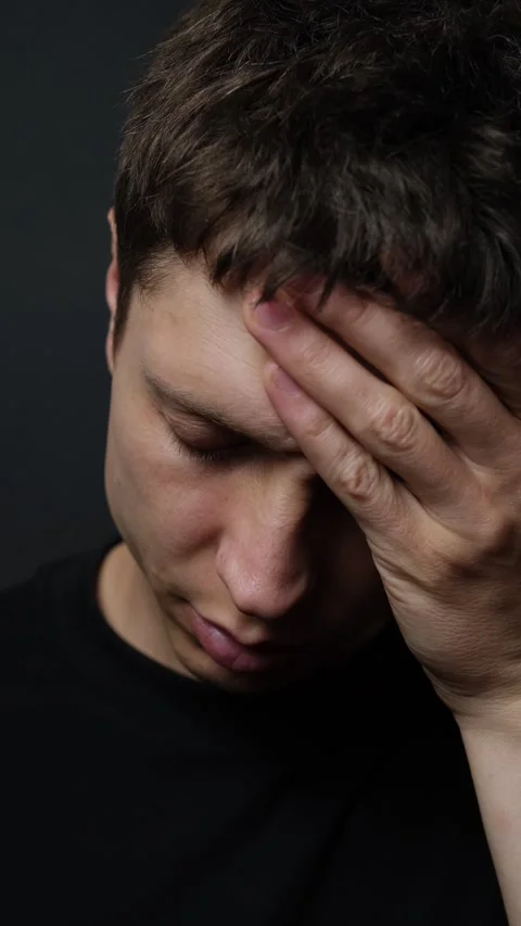 Close-up of young man holding head in pain on black background, headache stress Stock Footage 318066604