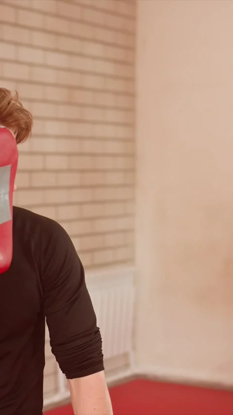 Close up of young man holding red boxing pad as another man rapidly strikes it Stock Footage 345547171