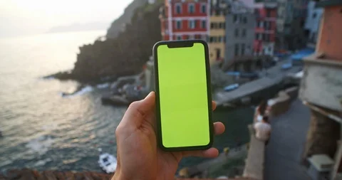 Close-up young man holding a smartphone scrolling on mockup green screen Stock Footage