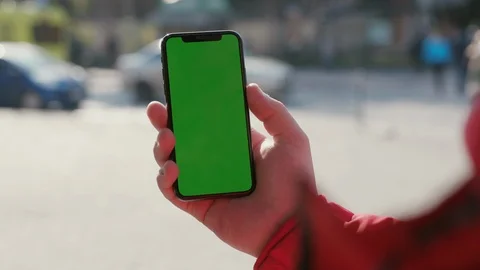 Close-up of young man holding vertical mobile phone with green display mock-up Stock Footage 117428325