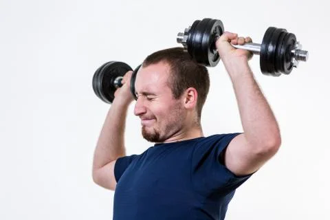 Close up of young man lifting weights over grey background Stock-Fotos
