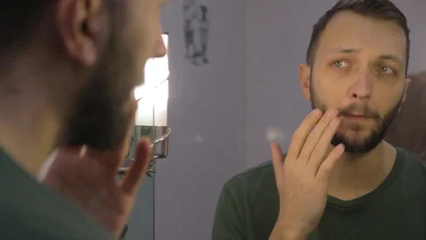 Close up young man looking at the mirror, checking face for skin diseases Video stock 104021901