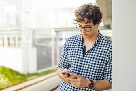 Close up of young man looking at mobile phone screen at metro station. Stock Photos