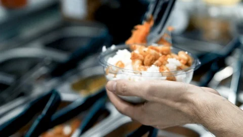 Close-up of a young man making a prawn poke bowl with rice and carrot salad Stock Footage 128926686