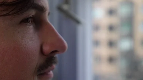 Close-up of young man with moustache smiling while looking through window 스톡 동영상 114871984