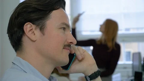 Close-up of young man with moustache talking on phone in office Stock-Footage 114871826