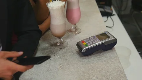 Close-up of a young man pays by a smart phone using NFC technology at a cafe Stock Footage 75808226