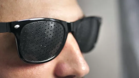 Close-up of a young man in perforated glasses for vision correction while Stock Footage 202612060