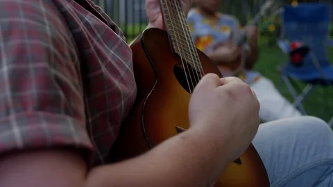 Close-up of a young man playing a small guitar in the backyard in the summer Video stock 116859819