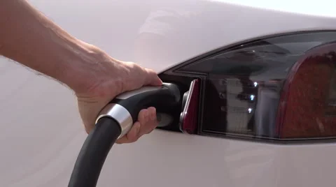 CLOSE UP: Young man plugging in Tesla white electric car at charging station Stock Footage 67222278