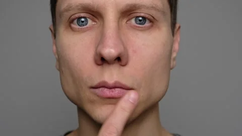 Close-up of a young man pointing to dry lips with his finger, emphasizing the ne Stock Footage 296883791