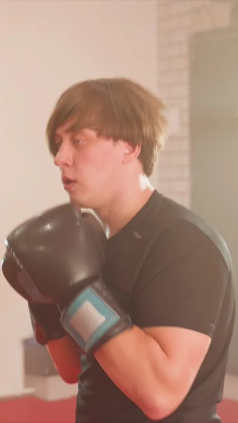 Close up of young man practicing boxing punches and stances in indoor gym with Stock Footage 343094186