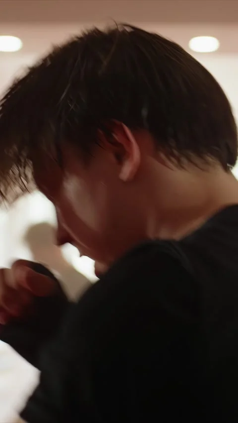 Close up of young man practicing boxing movements wearing black gloves in bright Stock Footage 346240602