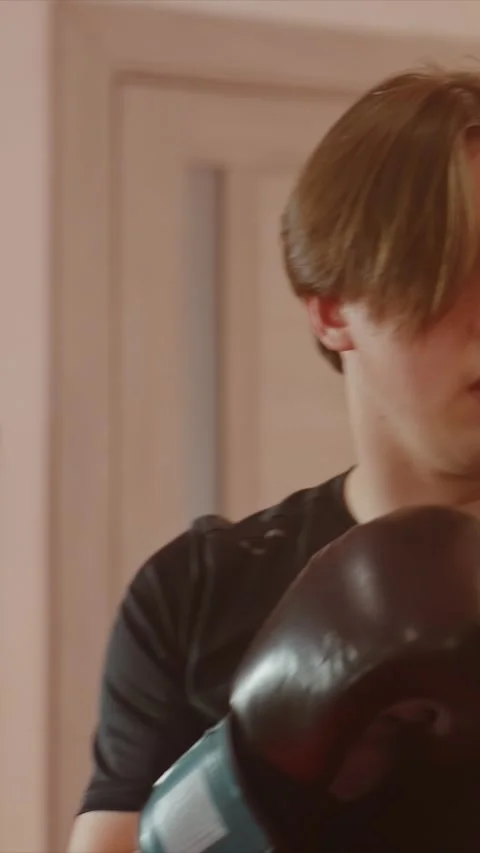 Close up of young man practicing punches with black gloves in bright light and Stock Footage 345549229