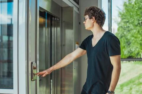 Close up of young man pressing the button of elevator at metro station. Stock Photos