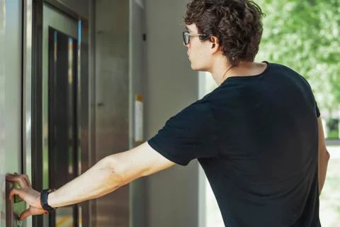 Close up of young man pressing the button of elevator at metro station. Stock Photos