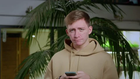 Close-up of a young man with problematic skin typing a message in his smartphone Stock Footage 195008566
