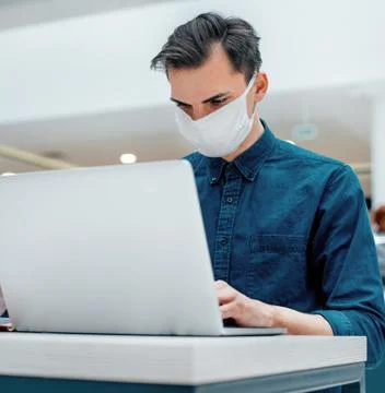 Close up. young man in a protective mask is working on a laptop Stock Photos