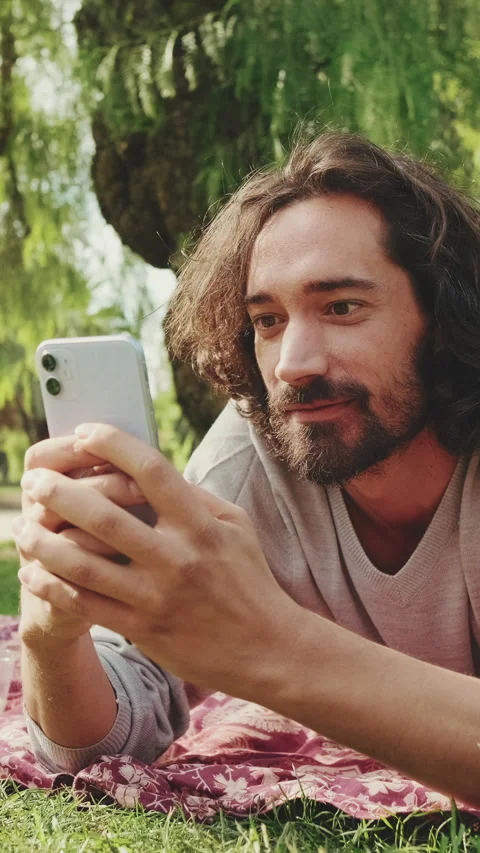 Close up, young man relaxing in the park and using mobile phone Vídeo Stock 227136014