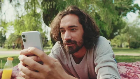 Close up, young man relaxing in the park and using mobile phone Stock Footage 227140377