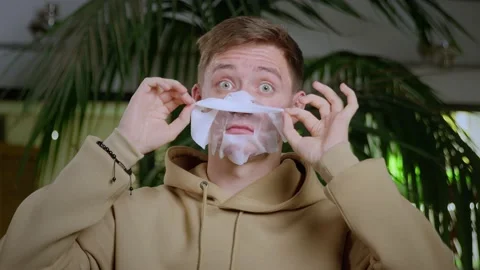 Close-up of a young man removing a fabric mask for skin care. Problematic skin Stock Footage 195012009