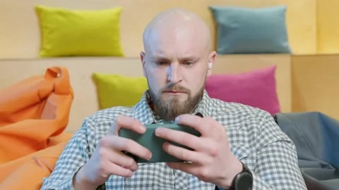 Close up of an young man sits on a bean bag while playing online using his phone Video stock 151914753
