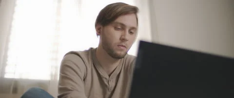A close up of a young man sitting in bed and working on a computer. Stock Footage 135095233