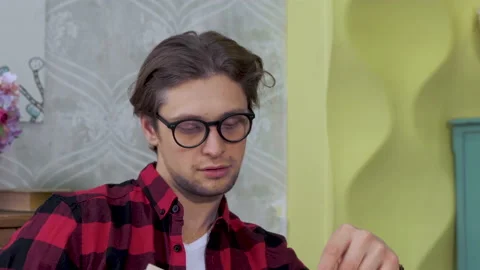 Close-Up Of A Young Man Sitting In A Bright Kitchen, Wearing Glasses Video stock 137092822