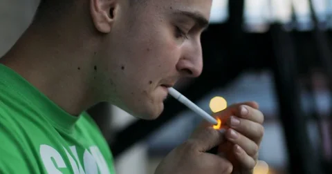 guys that smoke cigarettes close up of a young man smoking a cigarette outdoor. man smiles and smokes