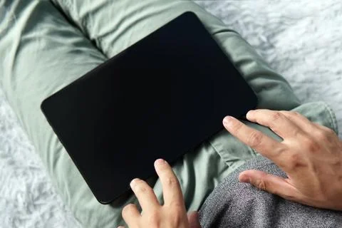 Close up of a young man on the sofa touching the black screen of a digital ta Foto stock