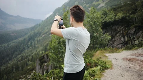 Close up young man stand take photo on phone in mountains feel happy smile Stock Footage 95450525