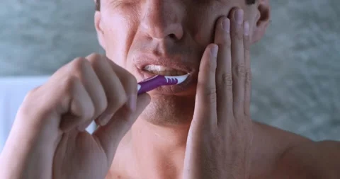 Close up young man suffers from tooth pain when brushes teeth with tooth brush Stock Footage 231948929