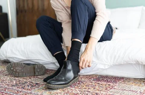 Close up of a young man is taking off his black patent leather boots at hotel Stock Photos