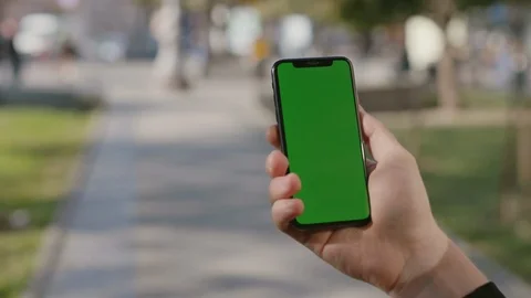 Close-up of young man typing on vertical smartphone with greenscreen and showing Stock Footage 117427508