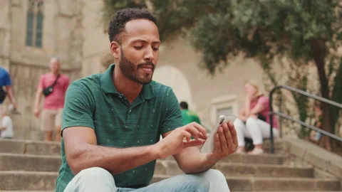 Close up, young man uses cellphone while sitting on the steps of the Sagrada Stock Footage 227101407