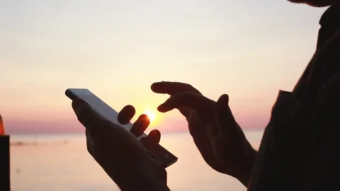 Close up of young man uses smartphone in beach cafe during sunset. 1920x1080 Stock Footage 88525127